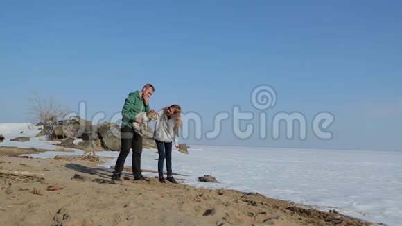年轻夫妇和狗在海滩上散步春天的海滩雪视频的预览图