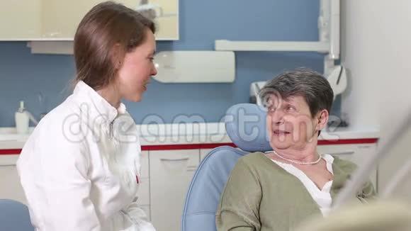 美丽的女牙医在与老年女性病人交谈视频的预览图