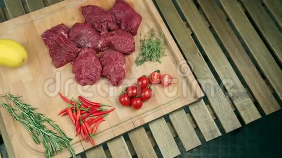 新鲜的肉做牛排在木板上炒肉牛肉靠近西红柿迷迭香百里香柠檬红辣椒蔓越莓视频的预览图