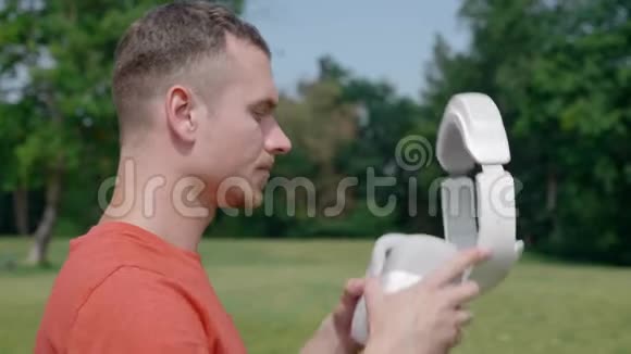 一个男人在公园里把一个VR耳机放在他的头上视频的预览图
