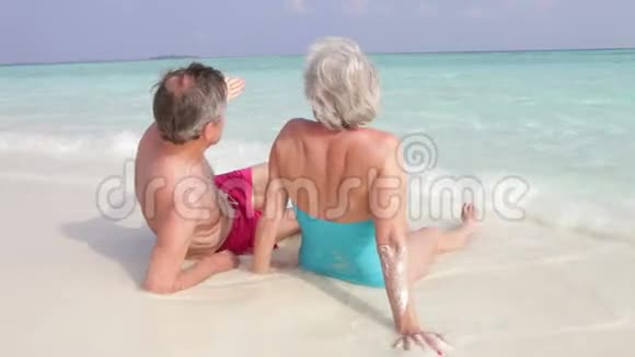 坐在美丽海滩上的高级夫妇的后景视频的预览图