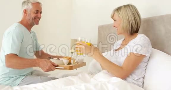 浪漫的丈夫带着微笑的妻子在床上吃早餐视频的预览图