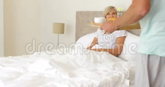浪漫的丈夫带着幸福的妻子在床上吃早餐视频的预览图