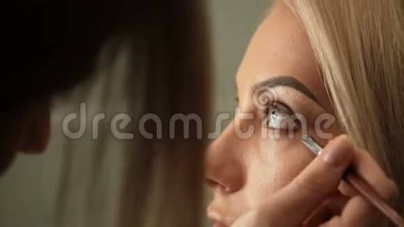 美容美发化妆师用一个梳头的金发女人画眉毛视频的预览图