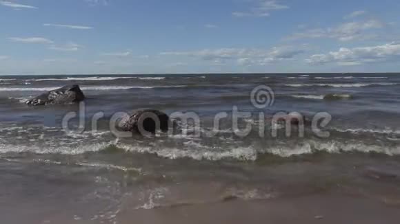 在夏季刮风的日子里海浪冲刷波罗的海沿岸的石头视频的预览图