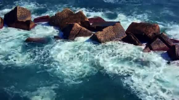 深绿色的海浪拍打着暗红色的岩石视频的预览图