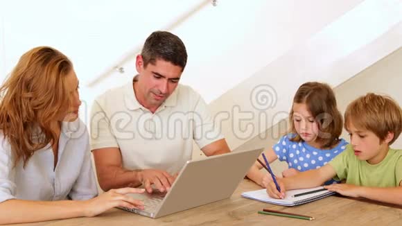 家长使用笔记本电脑孩子在餐桌上涂颜色视频的预览图