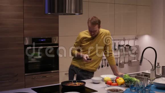 男人在厨房里用智能手机做饭视频的预览图