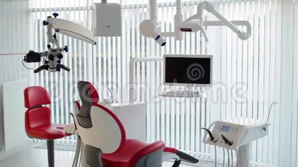 白色牙医办公室奢华的极简牙科诊所内部配有红色椅子和工具玻璃墙上的牙科灯视频的预览图