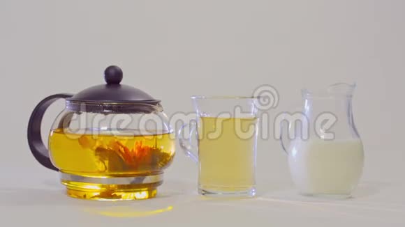 玻璃茶壶里的绿茶透明杯里的茶和一壶牛奶视频的预览图