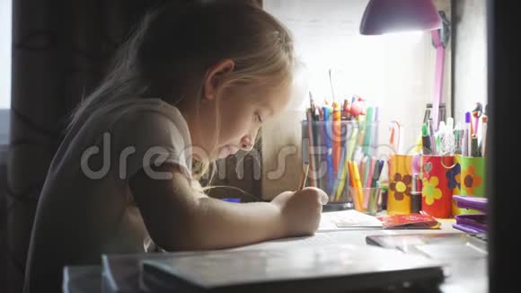 小女孩在灯光下在桌子上做作业小公主的创作爱好生活方式视频的预览图
