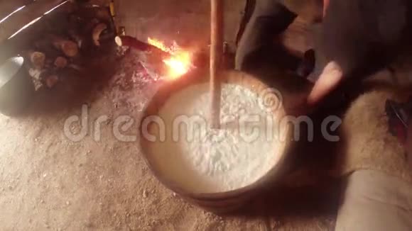 在篝火背景下旋转的牛奶木材压在木桶里视频的预览图