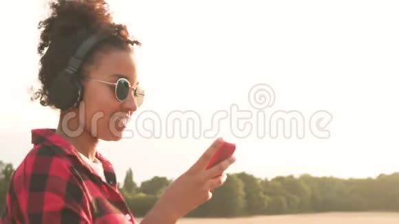 非裔美国少女少女使用手机和无线耳机听音乐视频的预览图