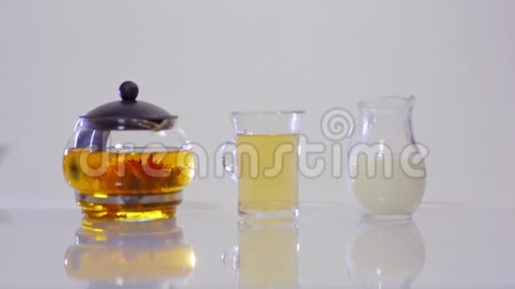 玻璃茶壶里的绿茶透明杯里的茶和一壶牛奶视频的预览图