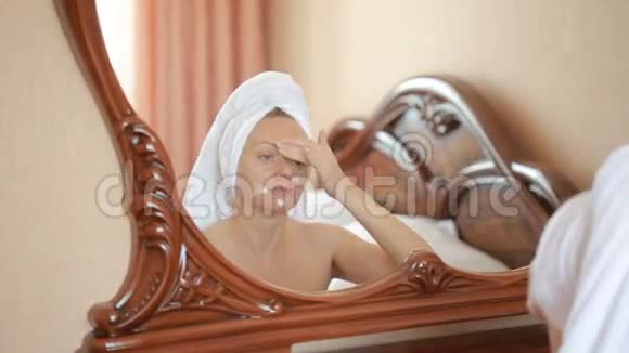 女人敷面膜保湿护肤霜在脸上照镜子视频的预览图