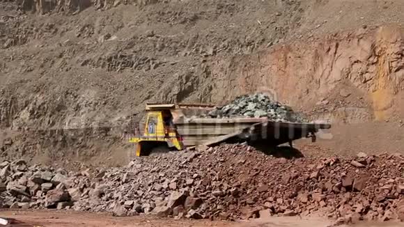 一辆大型翻斗车在职业生涯中挖掘一辆工业卡车在采石场挖货物一辆黄色的大型翻斗车视频的预览图
