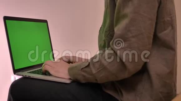 在办公室里用绿色屏幕在笔记本电脑上打字的特写镜头视频的预览图