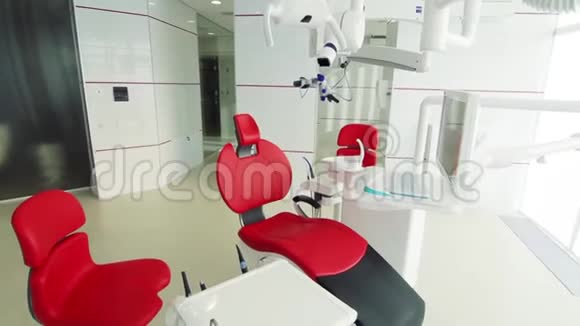 白色牙医办公室奢华的极简牙科诊所内部配有红色椅子和工具玻璃墙上的牙科灯视频的预览图