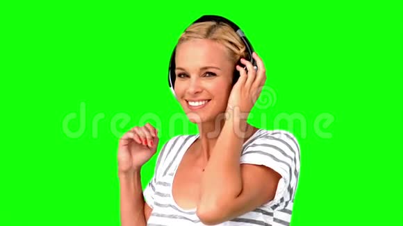 微笑的女人指着绿色屏幕上的相机视频的预览图