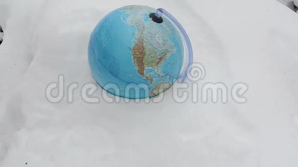 地球球体躺在冬天的雪地上戴手套放围巾视频的预览图