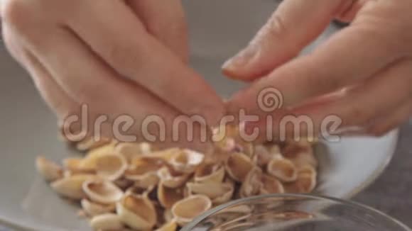 女子双手打开玻璃碗上方的开心果视频的预览图