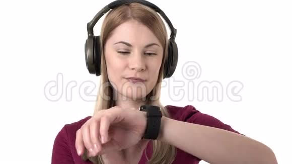 漂亮迷人的女士带着耳机在智能手表上听音乐孤立的白色背景视频的预览图
