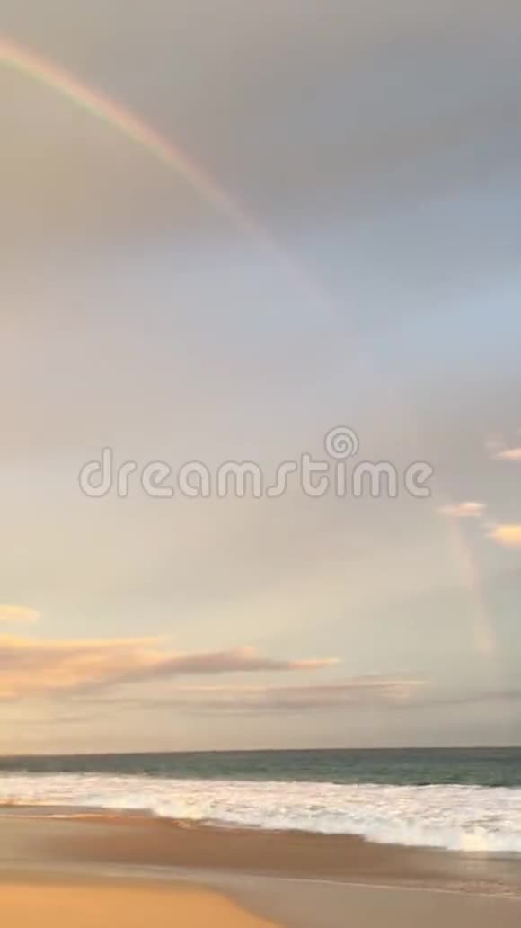 彩虹在日落时看到雨后从夏威夷考艾岛的凯卡哈海滩上的韦米亚峡谷和太平洋视频的预览图
