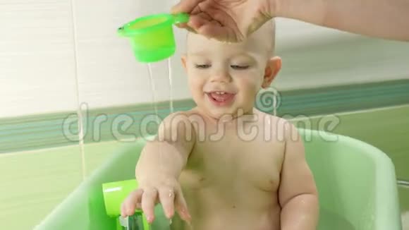 妈妈给漂亮的宝宝洗澡男孩在微笑玩着五颜六色的玩具和水一年左右的孩子视频的预览图