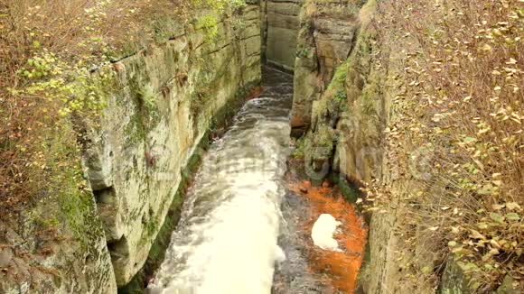 砂岩岩石之间快速满流的泡沫水肮脏的河岸上的橙色沉积物深深的河床变成了岩石视频的预览图