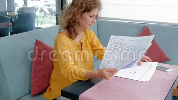 美丽的年轻女子在咖啡馆里浏览文件视频的预览图