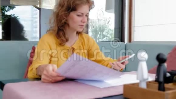 美丽的年轻女子在咖啡馆里浏览文件视频的预览图