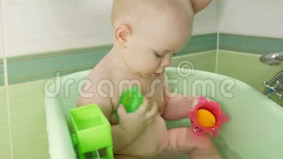 妈妈给漂亮的宝宝洗澡男孩在微笑玩着五颜六色的玩具和水一年左右的孩子视频的预览图