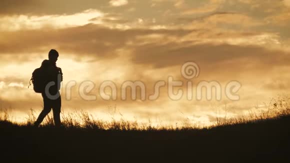 两个徒步旅行者的剪影带背包从山顶欣赏日落景色享受日落美景视频的预览图