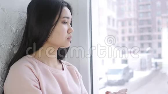 关闭年轻的亚洲女人看镜头窗户视频的预览图