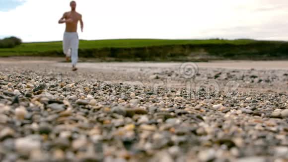 在海岸边慢跑的无衫男子视频的预览图