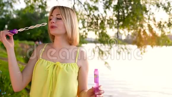 年轻漂亮的金发女郎在户外吹肥皂泡视频的预览图
