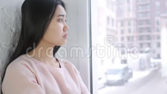 靠近年轻的亚洲女人透过窗户看视频的预览图