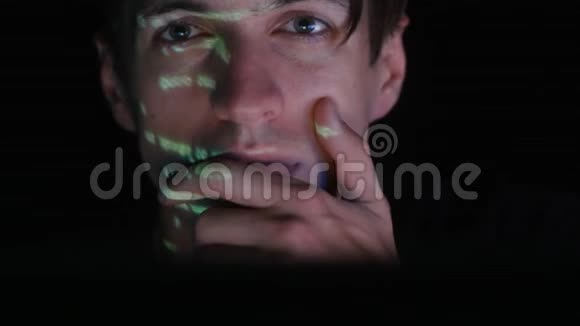 人类程序员黑客在电脑上工作而绿色代码字符反映在他的脸在黑暗的办公室房间视频的预览图