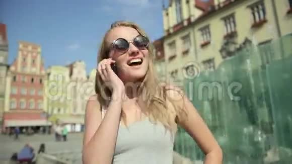 城市里戴太阳镜的开朗女人在手机上聊天视频的预览图