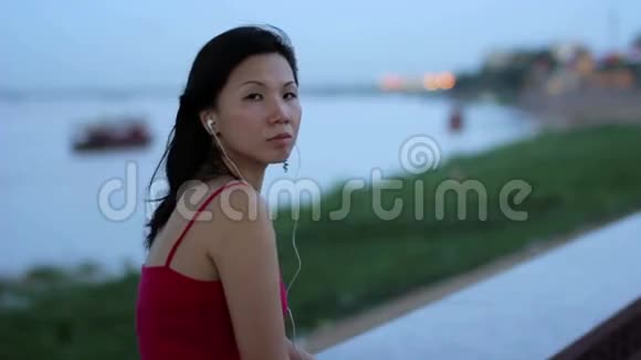 亚洲女商人下班后在河边听音乐视频的预览图