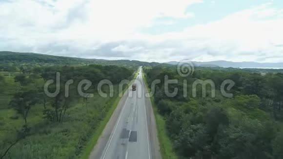 阳光明媚的一天汽车沿着空旷的乡村道路行驶上面的鸟瞰图视频的预览图