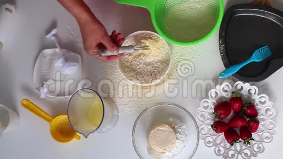 女人搅动面团并在面团中加入面粉桌子旁边是馅饼的原料视频的预览图