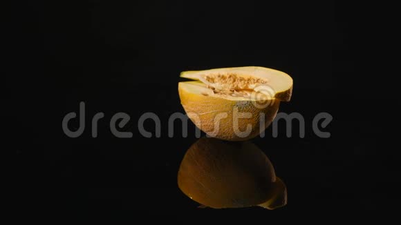 一个明亮多汁的甜瓜熟浆的一半在黑色背景上旋转切瓜天然和有机成分视频的预览图