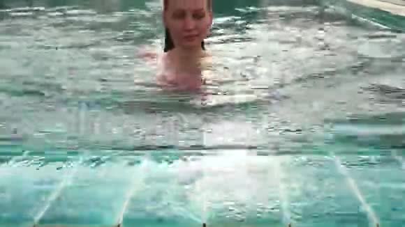 年轻女子在游泳池里放松和慢慢游泳视频的预览图