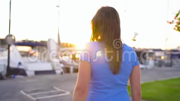戴墨镜的女人在日落时分带着很多游艇和小船沿着码头走关门视频的预览图