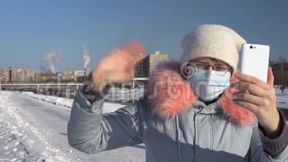 一个女人戴着面罩在冬天抽烟斗的背景下视频的预览图