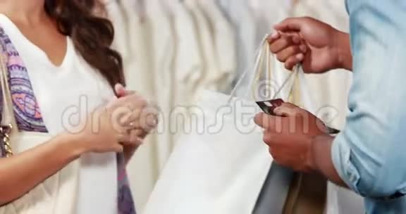 一位漂亮的黑发女郎在服装店用信用卡付款视频的预览图