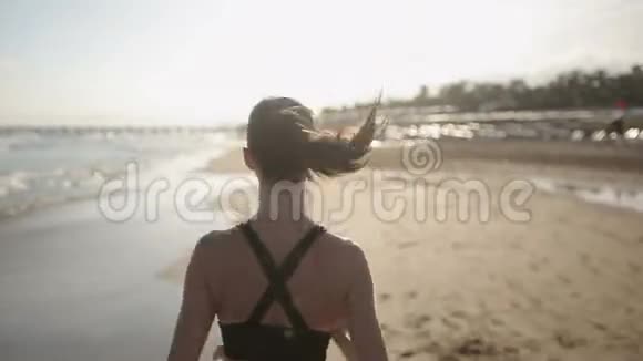 一个女人独自在美丽的日落海滩上奔跑视频的预览图