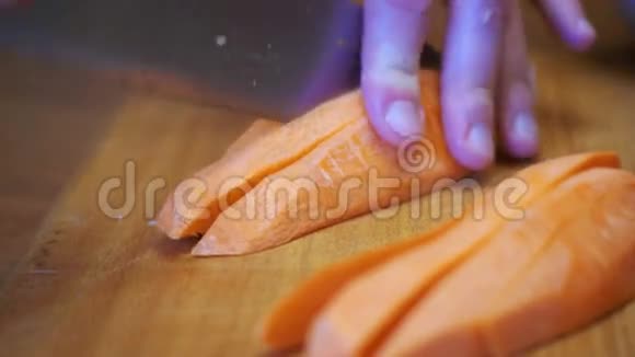 在家庭厨房的木制厨房板上用刀切割胡萝卜的女人手视频的预览图
