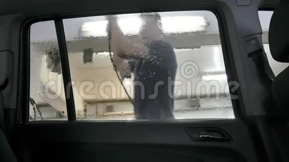 汽车经过洗车场时一个人用一个非接触式水槽清洗汽车从车内可以看到视频的预览图